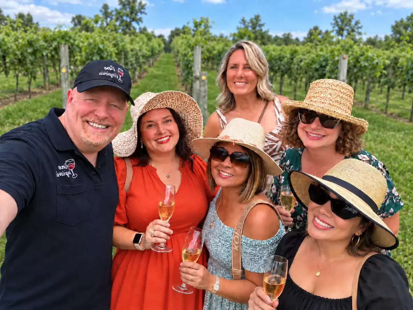 Four friends with glasses of wine standing among the vines