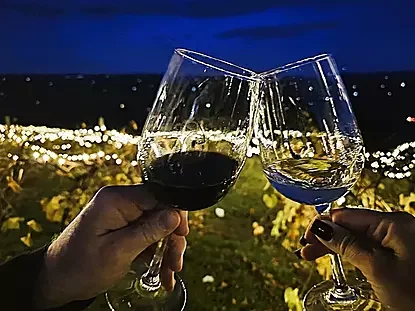 Clinking wine glasses over a Christmas  lite mountain side